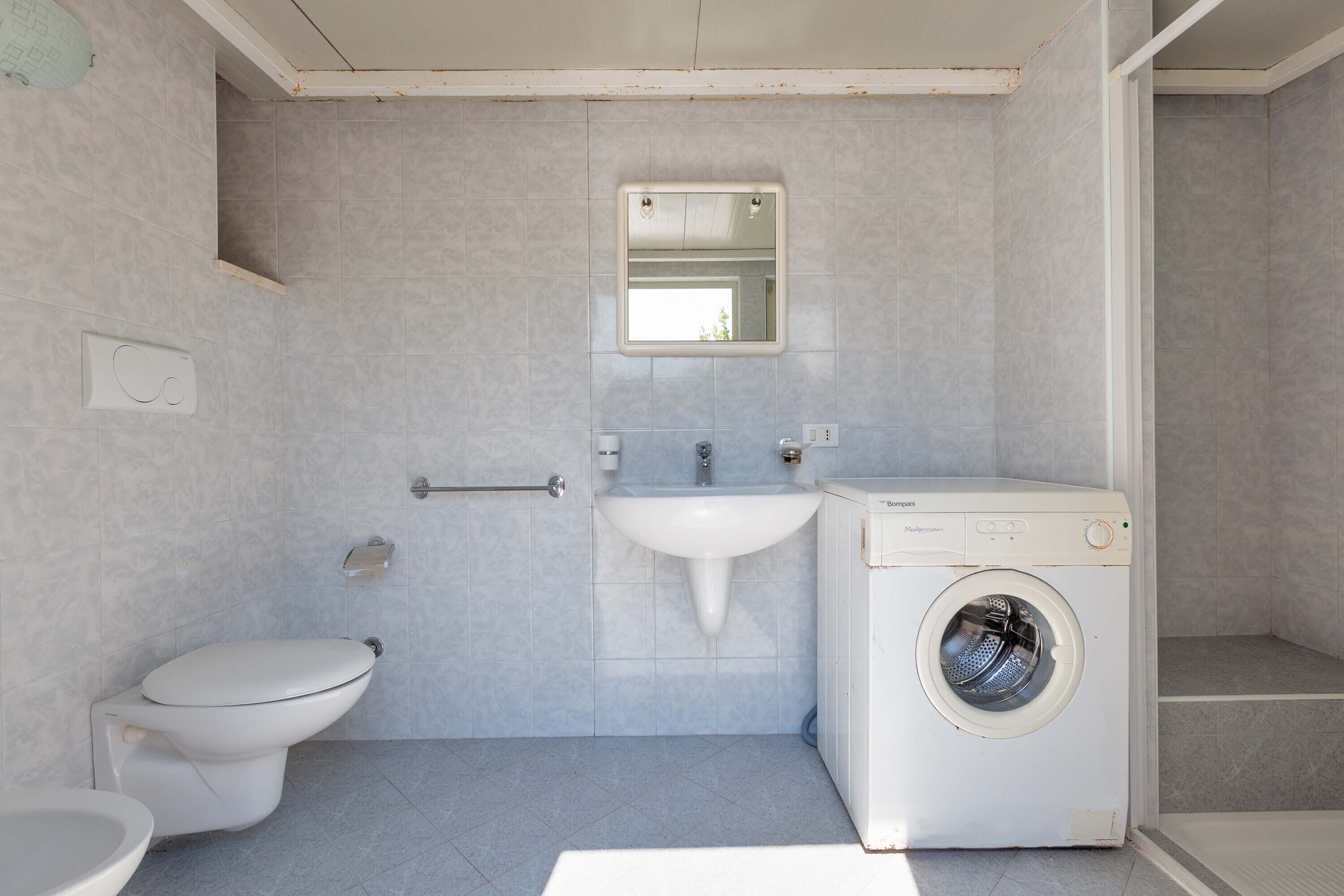 A compact bathroom with a toilet, sink, and washing machine.