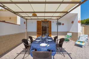 An outdoor patio with a covered dining table set for four, surrounded by wicker chairs. - 3033 Villetta Angela by Barbarhouse (Melendugno)