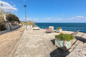 A coastal walkway with stone flooring, benches, and planters. - 2989 Villetta Mito - Mito A by Barbarhouse (Tricase)