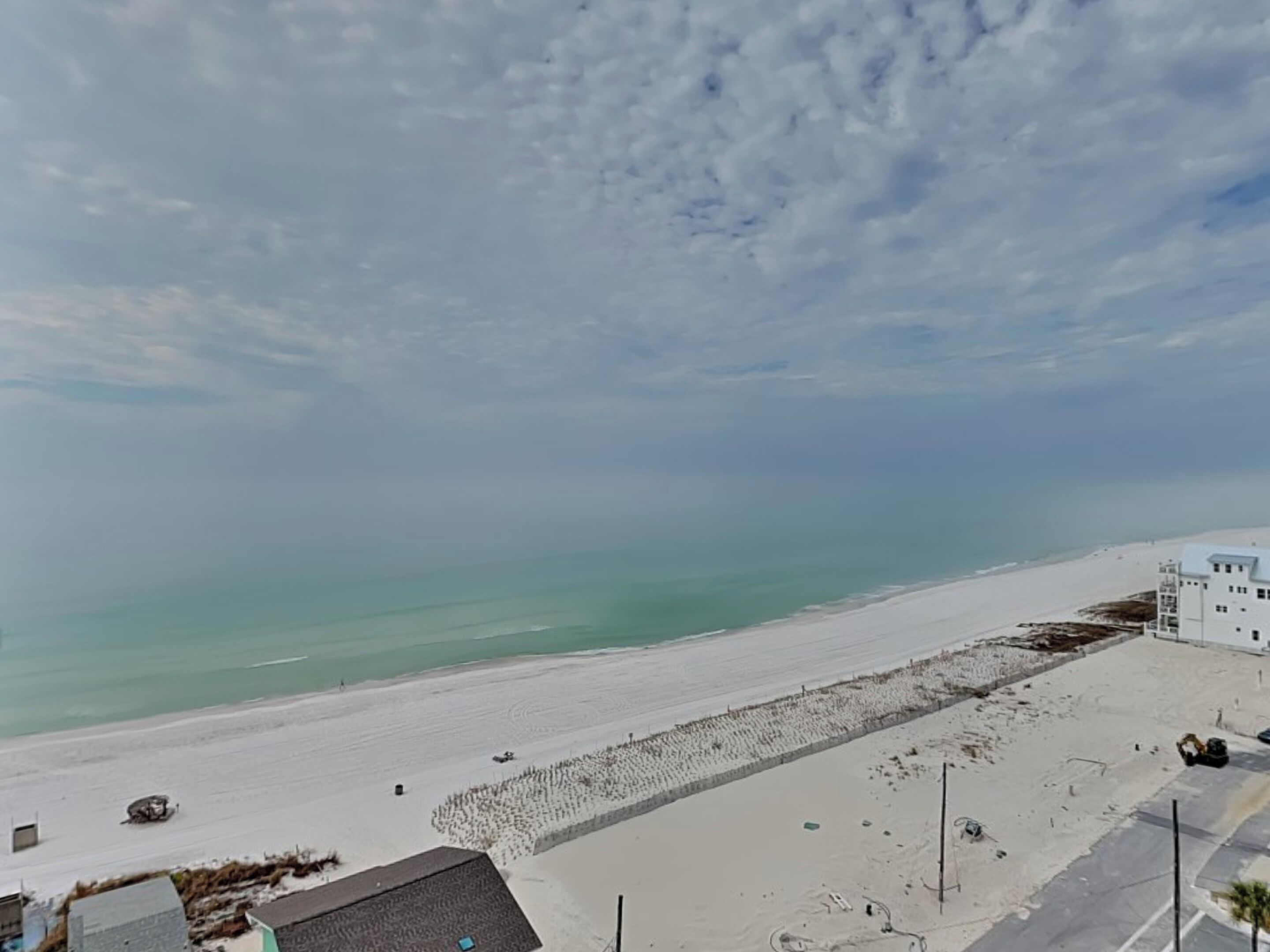 Une plage avec un bâtiment blanc et un ciel dégagé.