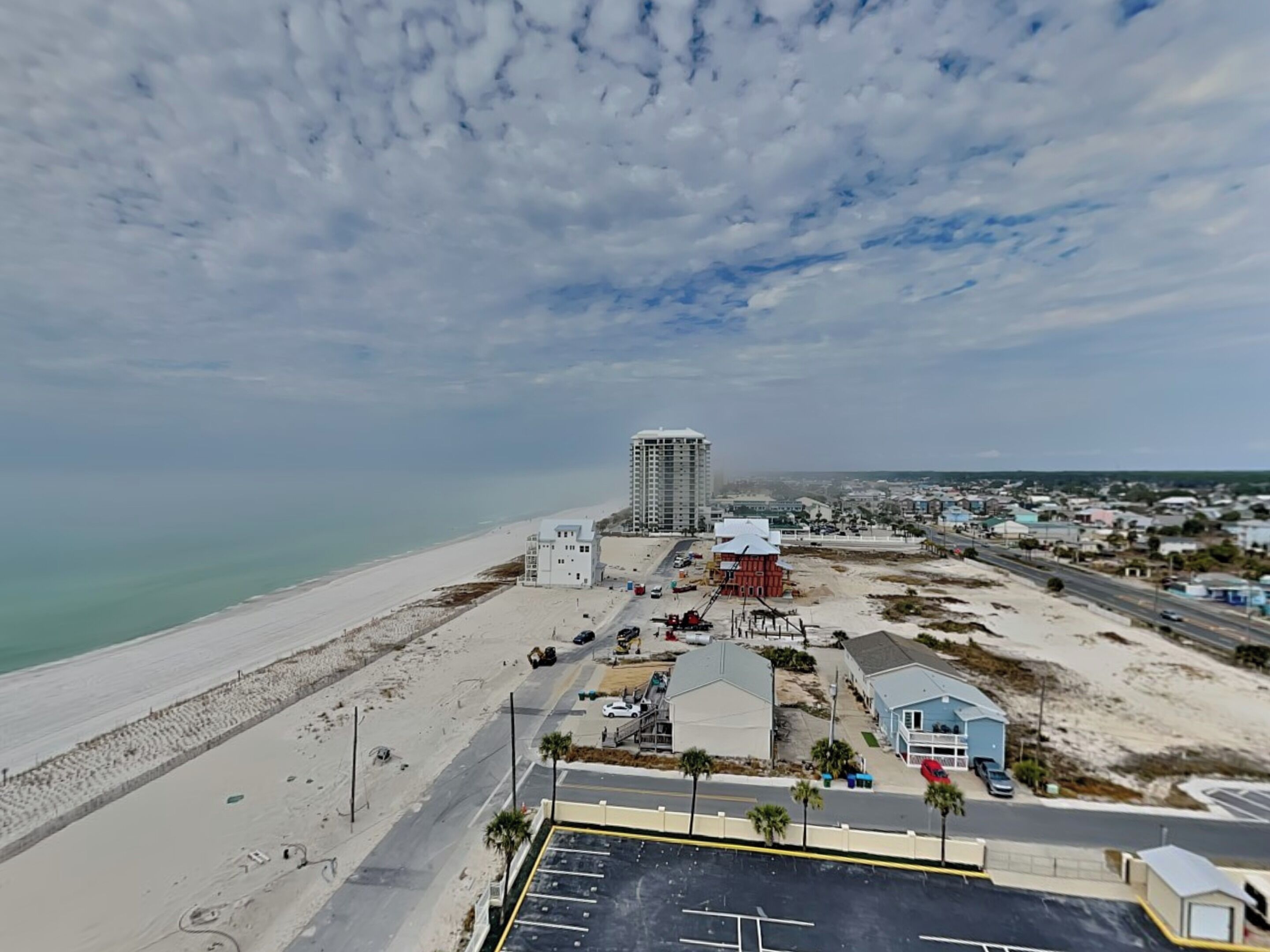 Une zone côtière comprenant une plage, un parking et quelques bâtiments, dont un grand hôtel.