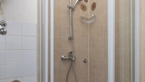 A shower area with a glass door, a handheld showerhead, and a wall-mounted faucet. - Sweetest Thing Apartment (Dubrovnik)