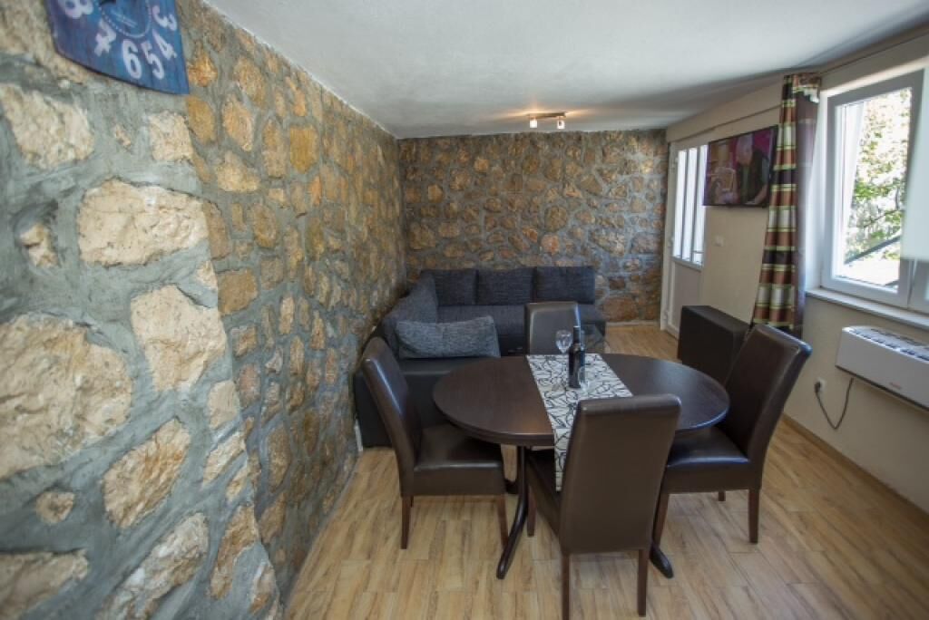 Una habitación con paredes de piedra, un sofá y una mesa redonda con sillas.