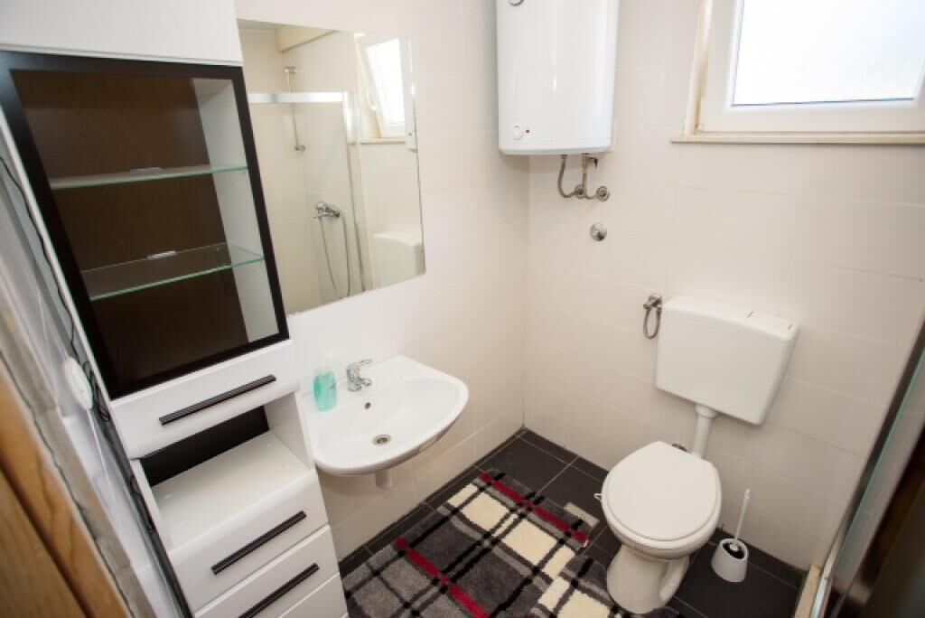 A small bathroom with a toilet, sink, and mirror.