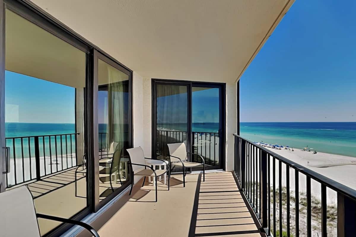 A balcony with a view of the beach and ocean.