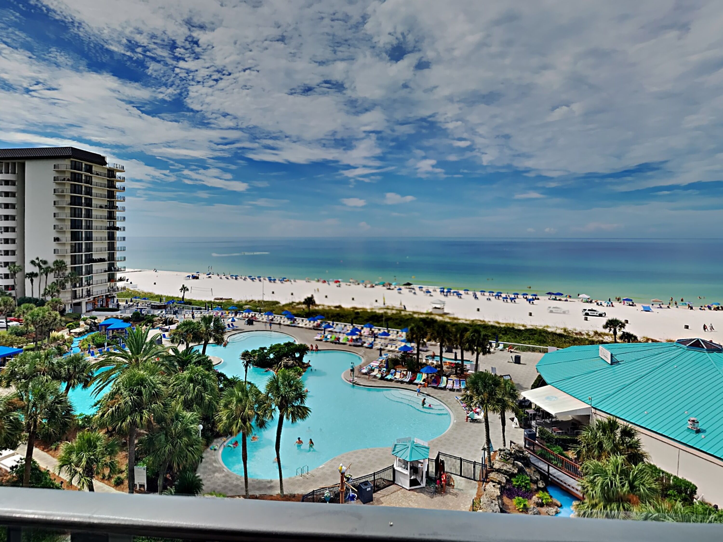 A resort with a large pool area, a beach, and a high-rise building.