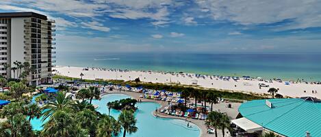 A resort with a large pool area, a beach, and a high-rise building.