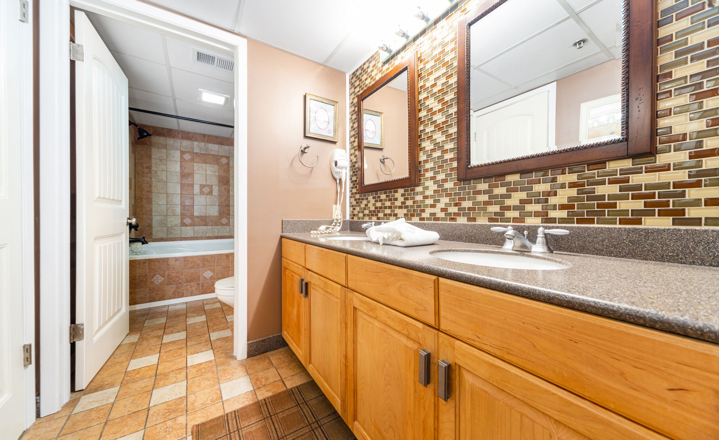 A bathroom with a wooden vanity, a sink, a mirror, and a shower area.