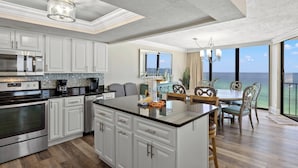 A modern kitchen with white cabinetry, stainless steel appliances, and a large island. - Edgewater Beach & Golf Resort VIII by Resort Collection (Panama City Beach)