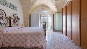 A bedroom with a bed, a wardrobe, and a stone archway. - 2923 La Casa Della Nonna by Barbarhouse (Carpignano Salentino)