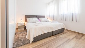 A modern bedroom with a large bed, a bedside table, and a nightstand. - Apartment Luce Royal (Dubrovnik)