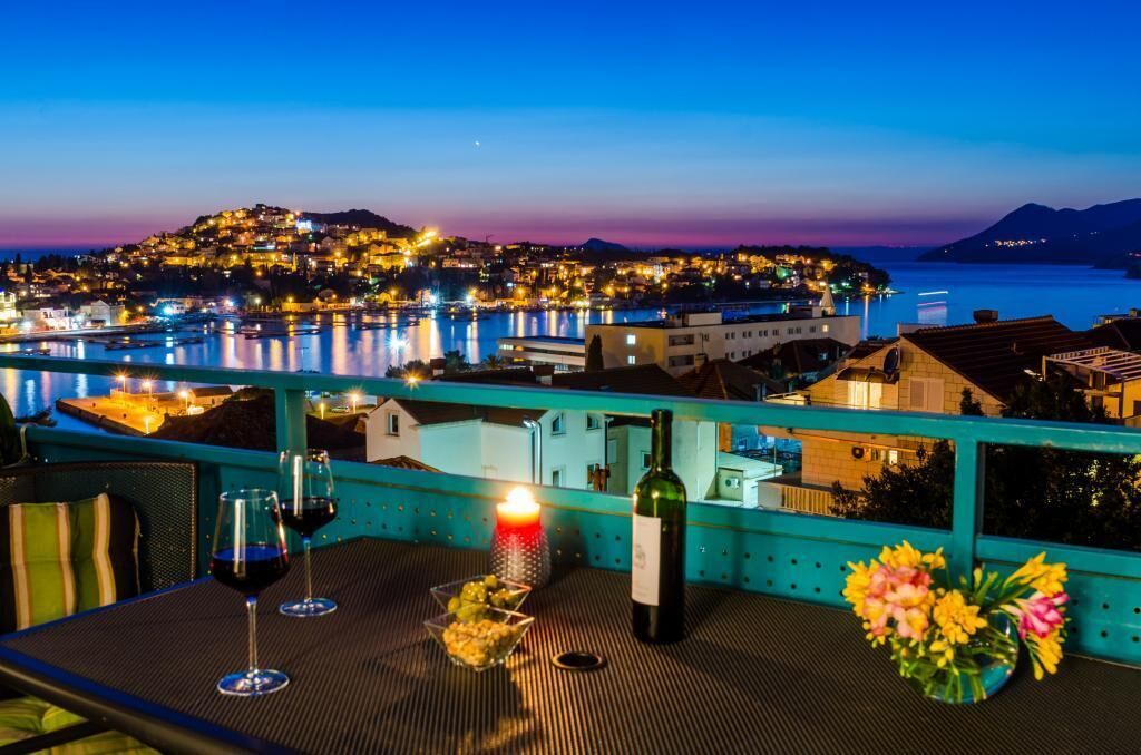 Une terrasse avec une table dressée pour deux personnes, une bouteille de vin et une bougie.