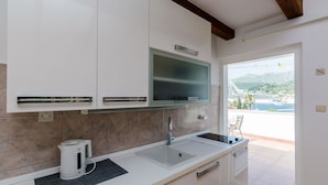 A modern kitchen with white cabinets, a stainless steel sink, and a built-in oven. - Apartment Marina View (Dubrovnik)