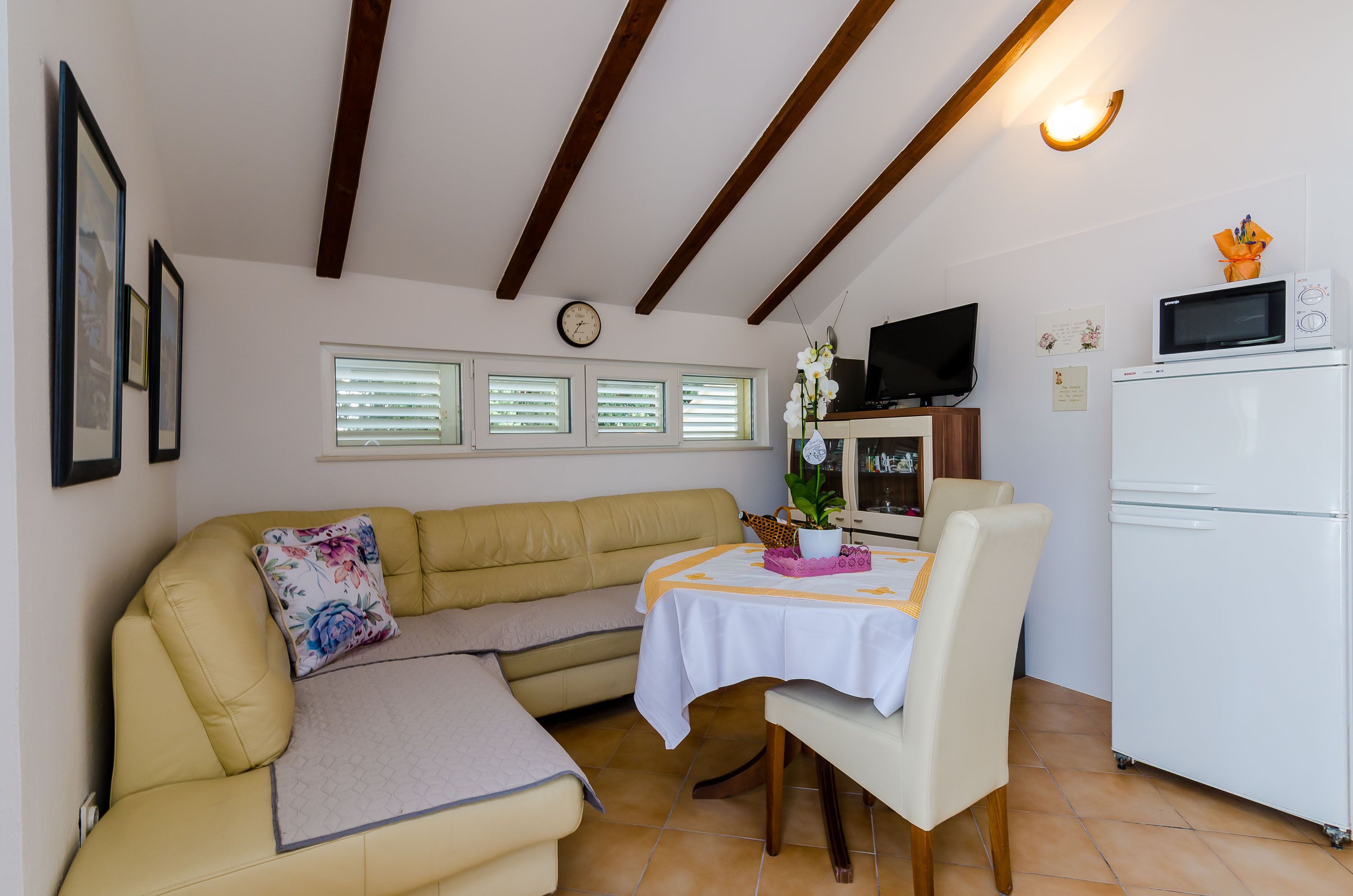A cozy living area with a sofa, a dining table, and a white refrigerator.