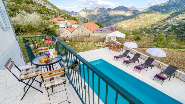 A poolside area with a view of mountains, a table with chairs, and a bench. - Country Home Matkovic - Duba (Konavle)