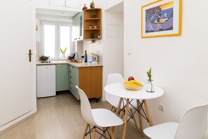 Una cocina moderna con armarios blancos, una mesa de comedor de madera con sillas blancas, y una obra de arte enmarcada en la pared.