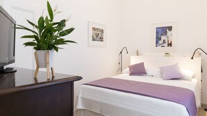 A bedroom with a bed, a desk, a plant, and two framed pictures on the wall. - Apartment Toni (Dubrovnik)