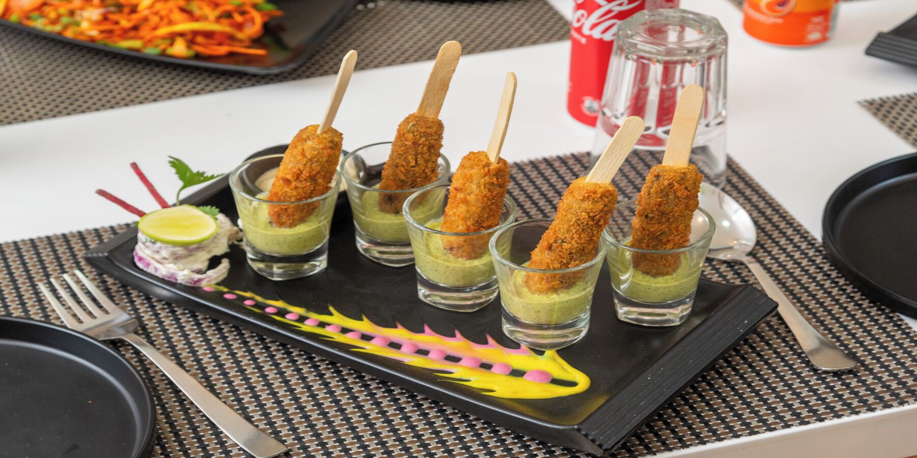 A tray with mini desserts, a fork, a spoon, and a Coca-Cola bottle.