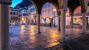 An open courtyard with stone flooring and arches, surrounded by buildings with balconies and windows. - Casa Palmaverde Few Min From Lake (Riva del Garda)