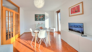 A modern dining area with a round table, white chairs, and a large pendant light. - Casa Palmaverde Few Min From Lake (Riva del Garda)