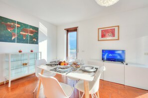 Un coin repas avec une table dressée pour deux personnes, un téléviseur posé sur un meuble et une carte du monde accrochée au mur.