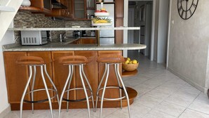 Une cuisine moderne dotée d’un îlot central, d’appareils électroménagers en acier inoxydable et de tabourets de bar en bois.