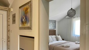 Une chambre à coucher avec un lit, un luminaire suspendu et un tableau au mur.