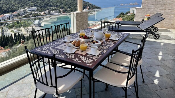 Un balcon avec une table préparée pour le petit-déjeuner, offrant une vue sur la côte.