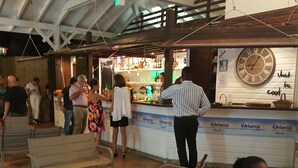 A bar area with a clock, chairs, and a counter. - Studio with sea view, beach, air conditioning, swimming pool, bar-restaurant, car rental (Sainte-Anne)