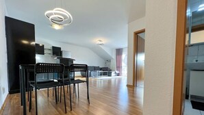 Uma cozinha moderna com forno embutido e micro-ondas, uma área de jantar com mesa e cadeiras de madeira, e uma janela grande que proporciona muita luz natural.