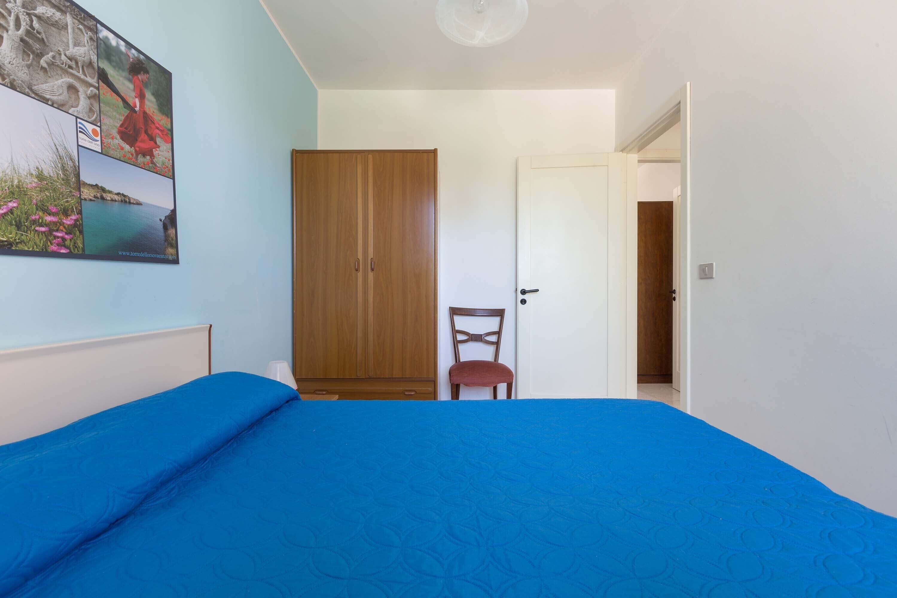 Une chambre à coucher comprenant un lit, une armoire, une chaise et une porte donnant sur une autre pièce.