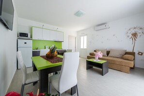 Un salón moderno con una mesa de comedor verde, sillas blancas, un sofá marrón y una pequeña mesa de centro.