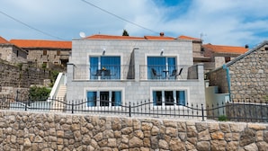 A two-story building with a stone facade, multiple balconies, and a stone wall in the foreground. - Villa Kabalero (Konavle)