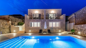 A two-story building with a swimming pool, outdoor seating, and stone walls. - Villa Kabalero (Konavle)
