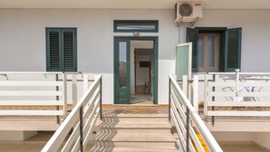 Une entrée d’immeuble avec une porte, un escalier et un balcon doté de balustrades.