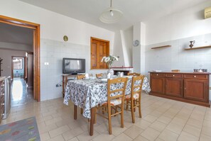A dining area with a table set for four, a television, and a wooden cabinet with shelves. - 2994 La Casa di Cesaria by Barbarhouse (Martano)