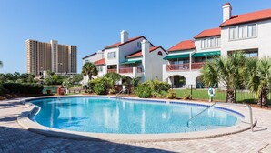 A swimming pool surrounded by a brick patio, with a building in the background.