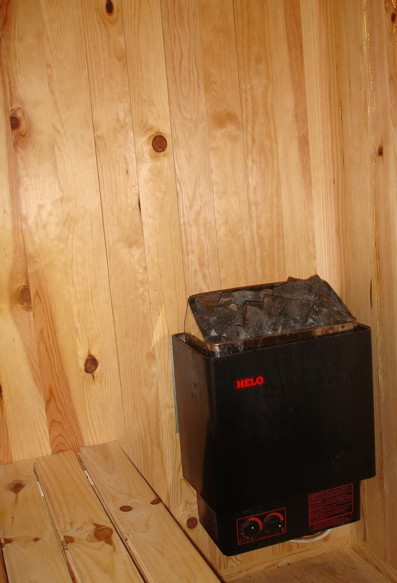 Un termosifone nero HELO in una baita in legno con pavimento e pareti in legno.