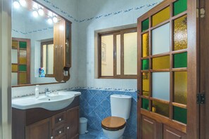 Une salle de bain avec un meuble-lavabo en bois, un évier et des toilettes.