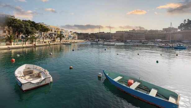 A harbor with boats, a fort, and buildings along the waterfront.