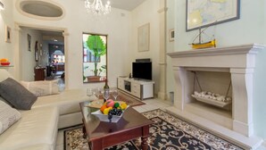 A living room with a sofa, coffee table, TV, fireplace, and a map on the wall.