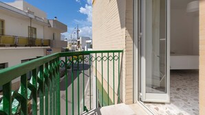 A balcony with a green metal railing, a sliding glass door, and a terrazzo floor. - 2483 La Casa di Maristella - Trilo by Barbarhouse (Otranto)