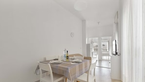 A dining area with a table set for four, white chairs, and a striped tablecloth. - 2483 La Casa di Maristella - Trilo by Barbarhouse (Otranto)