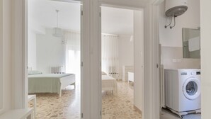 A modern, well-lit hotel room with a bed, a desk, and a washing machine. - 2483 La Casa di Maristella - Trilo by Barbarhouse (Otranto)
