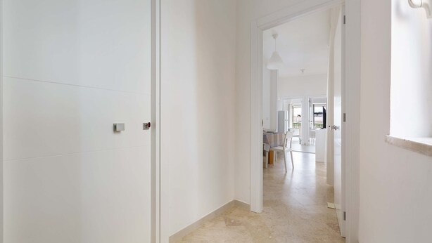 A hallway with white walls and doors, leading to a dining area with a table and chairs. - 2483 La Casa di Maristella - Trilo by Barbarhouse (Otranto)