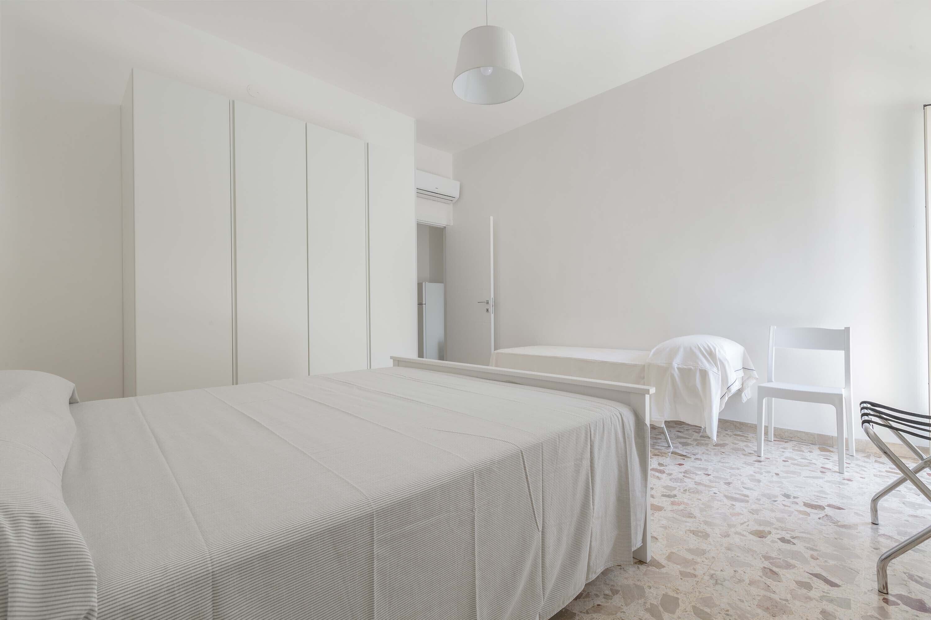 Ein schlicht eingerichtetes Schlafzimmer mit einem großen Bett, einem Sessel und einem Schreibtisch.