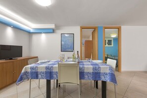A dining area with a table set for two, a television on a cabinet, and a framed picture on the wall. - 2703 Villino Mare Blu by Barbarhouse (Melendugno)