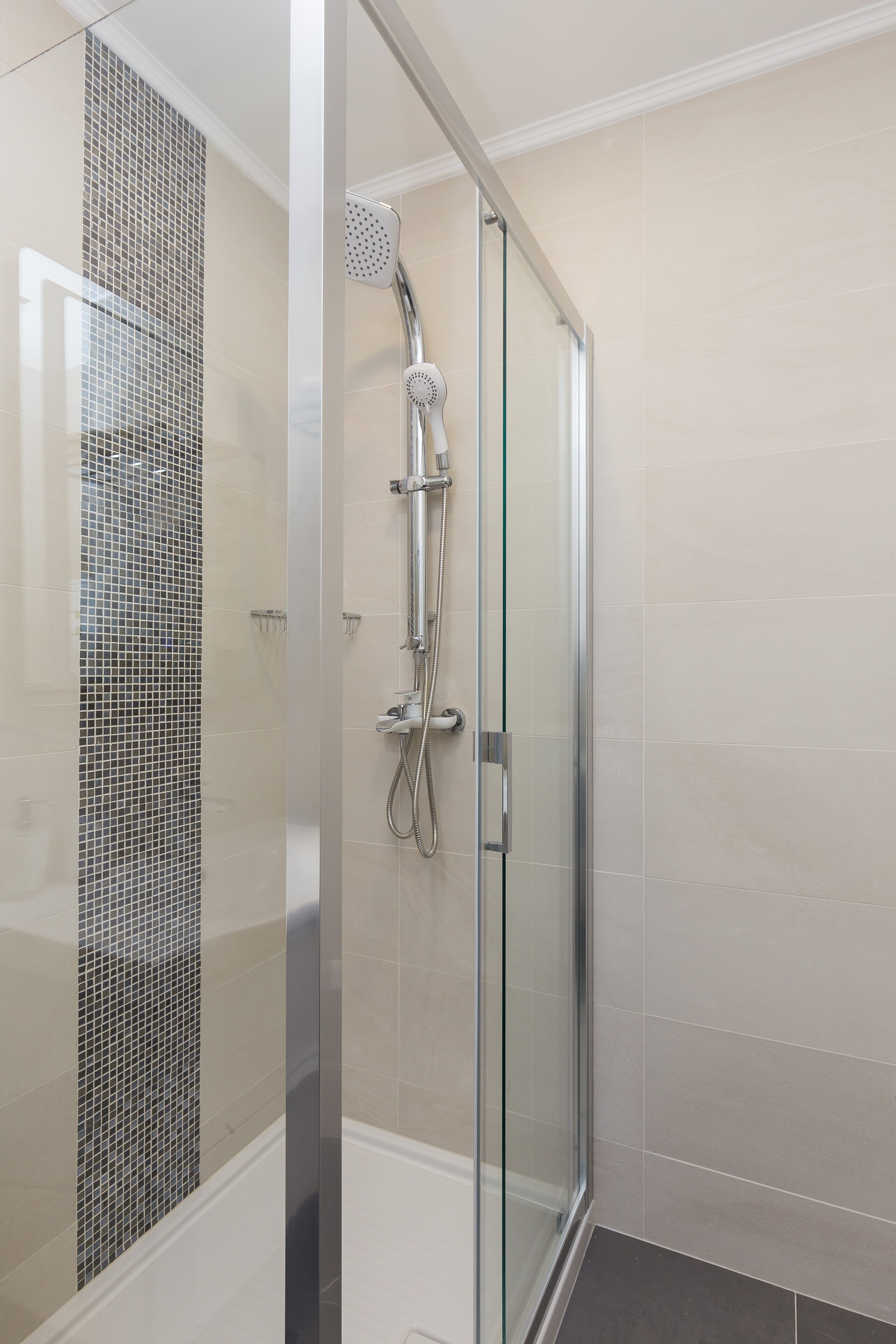 A modern shower with a glass door and a tiled wall.