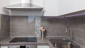 A modern kitchen with a built-in stove, stainless steel sink, and a range hood. - Apartment H&D (Dubrovnik)