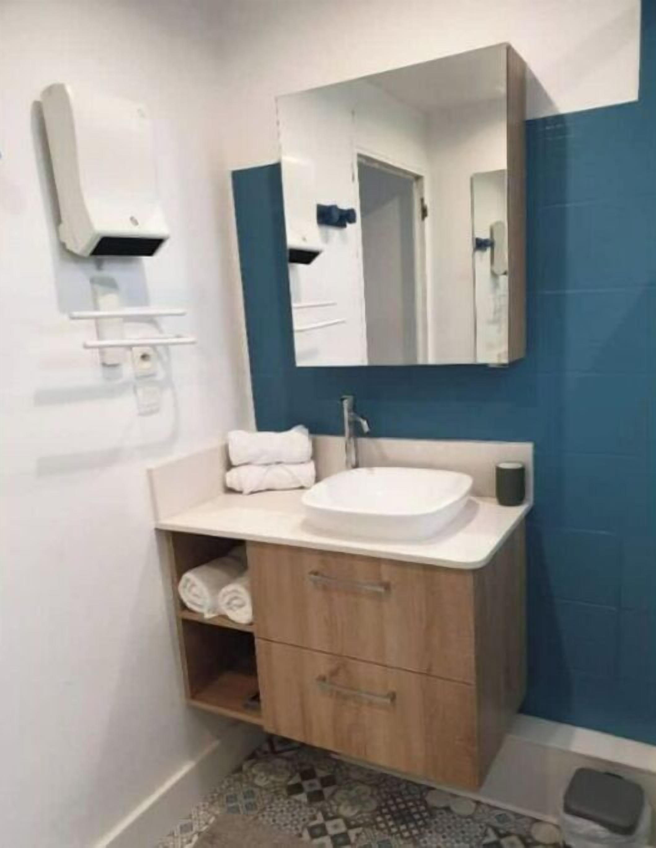 Une salle de bain avec un lavabo blanc, un miroir, un porte-serviettes et un meuble en bois.